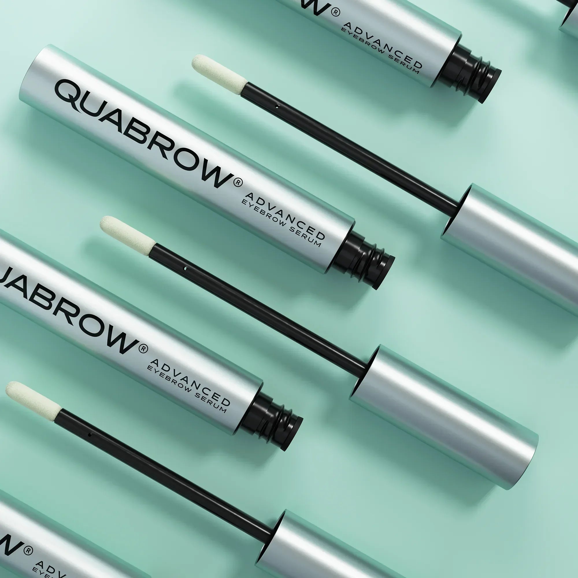 Multiple QUABROW Advanced Eyebrow Serum tubes from the Trio Set displayed on a mint green background