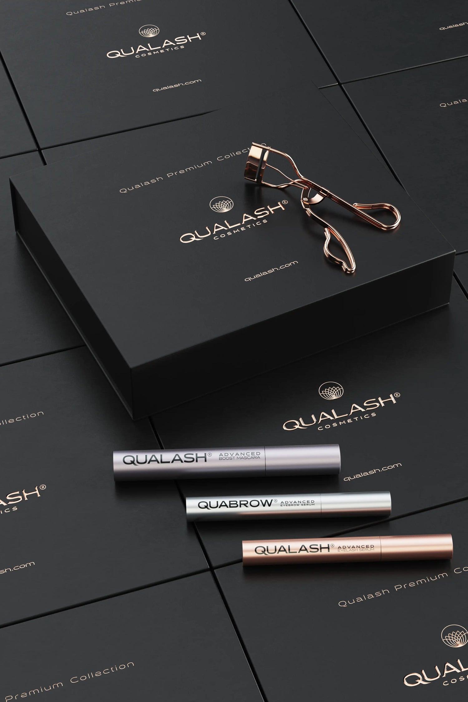 Flatlay of Qualash Premium Collection with curler and serums displayed outside the box